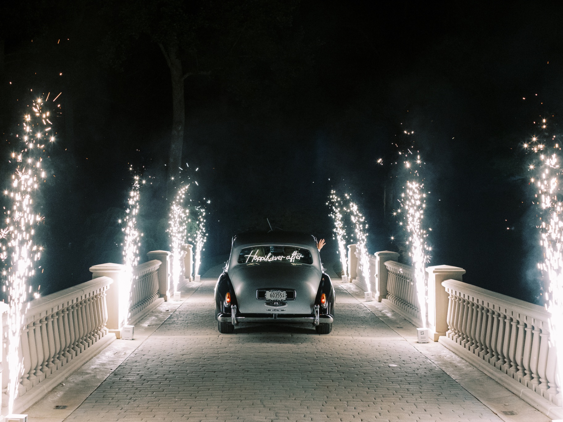 Vintage Rolls-Royce driving through a tunnel of cold spark fountains after a wedding
